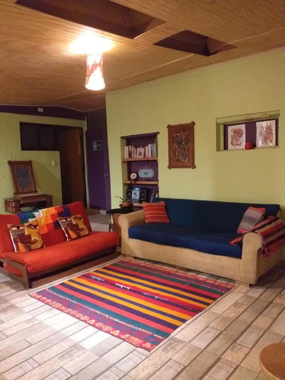 圣佩德罗·德·阿塔卡马Hostal Ayni的客厅配有沙发和色彩缤纷的地毯