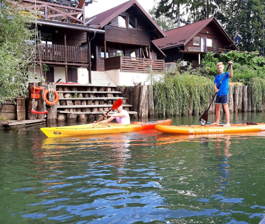 卢布尔雅那River Houses Ljubljanica的两个男孩在水面上,在房子前面划皮艇