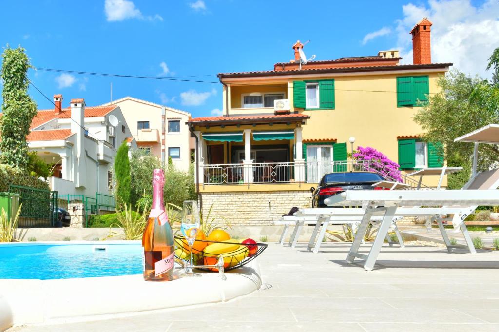 扎达尔Villa Lux Nina with six bedrooms, private pool, sauna的一瓶葡萄酒和一碗水果,位于房子旁边