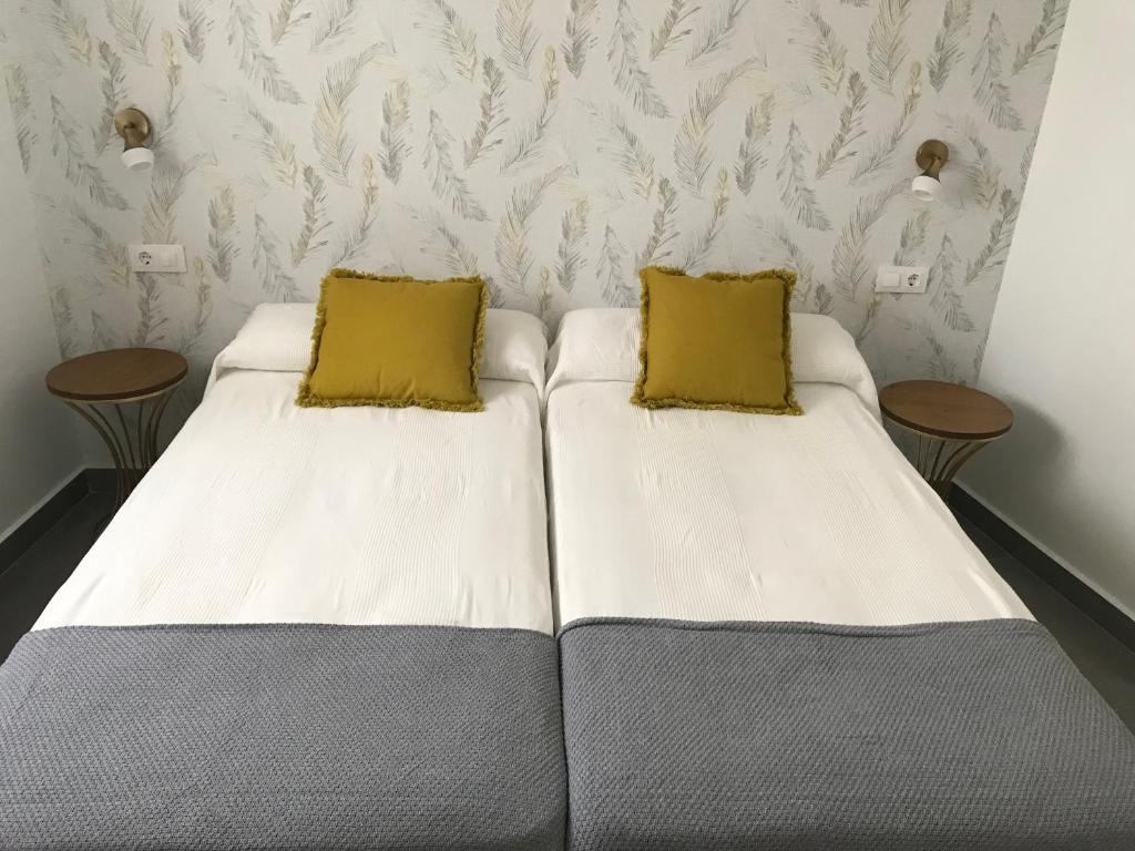 梅里达Apartamentos Ad Theatrum的两张带两张黄色枕头的床铺