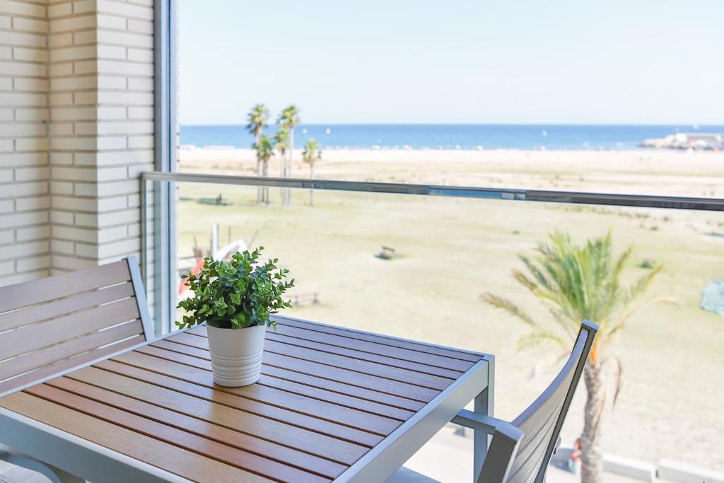 科马鲁加Apartaments Les Palmeres Coma-ruga的俯瞰海滩的阳台配有带盆栽植物的木桌