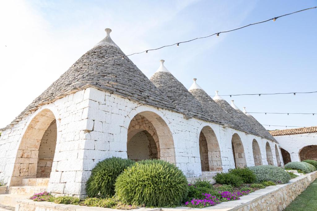 CrispianoMasseria Pilano的白色砖砌的建筑,有拱门和植物