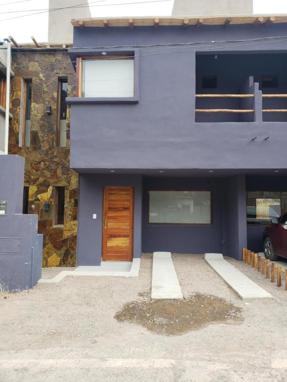 普尔马马尔卡Lo del Chango的一座带木门和建筑的蓝色房子