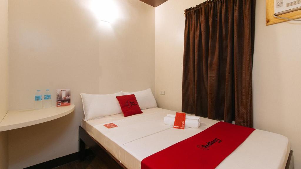 马尼拉RedDoorz near EDSA Camp Crame的小房间,床上配有红色枕头