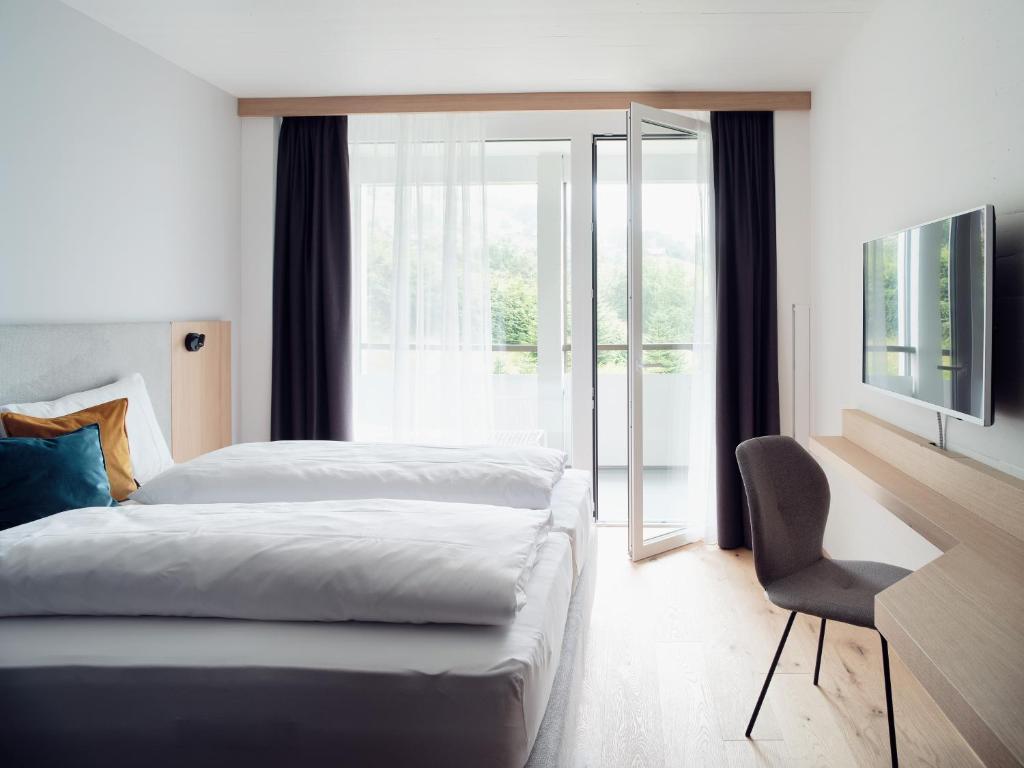 QuartenHotel Neu-Schönstatt的卧室配有床、椅子和窗户。