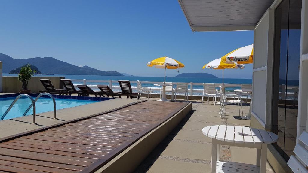 乌巴图巴Hotel Maranduba的海滩上带椅子和遮阳伞的游泳池