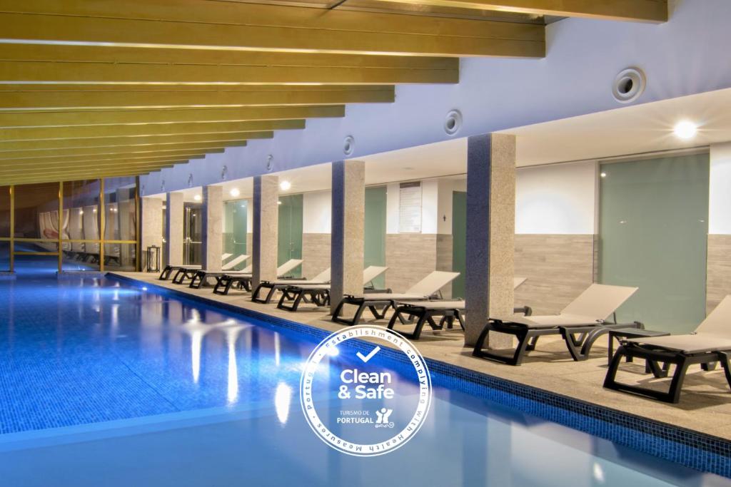 科维良Luna Hotel Serra da Estrela的游泳池配有椅子和标志,干净而安全