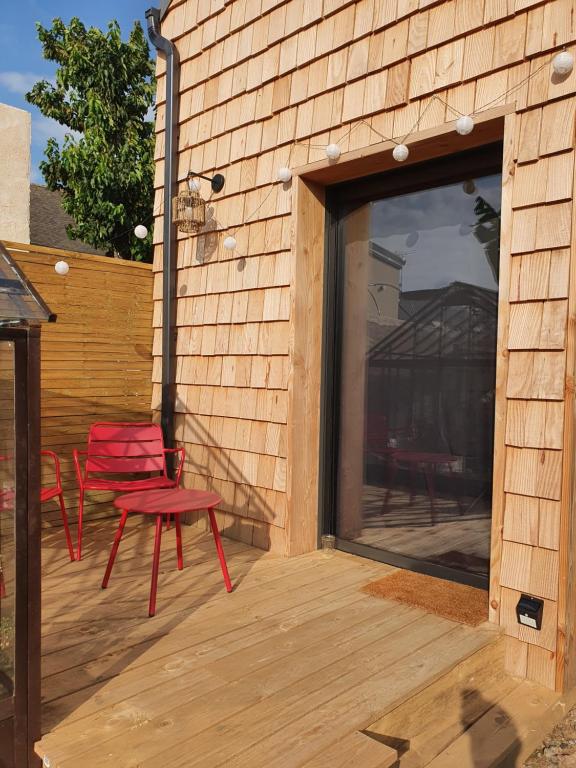 昂热Tiny House Cosy 2 - Angers Green Lodge的一个带两张红色椅子的庭院和大窗户