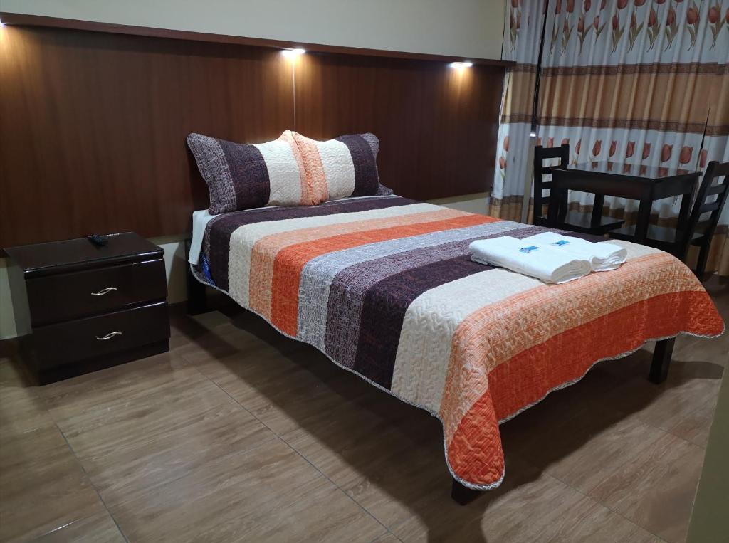 瓦努科Lembranças Hotel的一间卧室配有一张带条纹毯子的床和床头柜