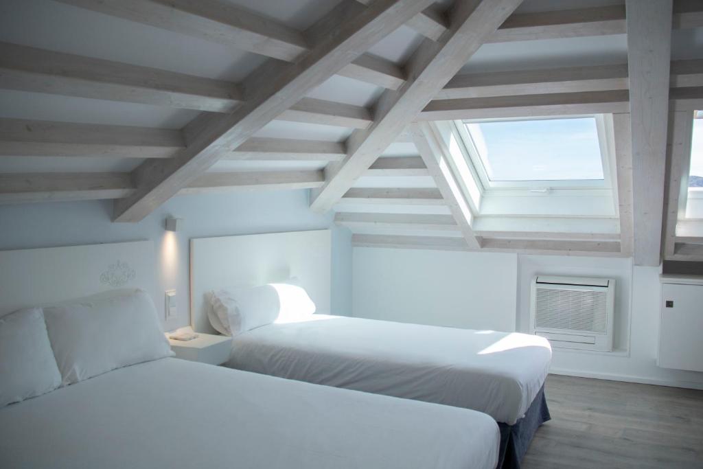 圣地亚哥－德孔波斯特拉Hotel Alda San Bieito的白色客房的两张床,设有窗户
