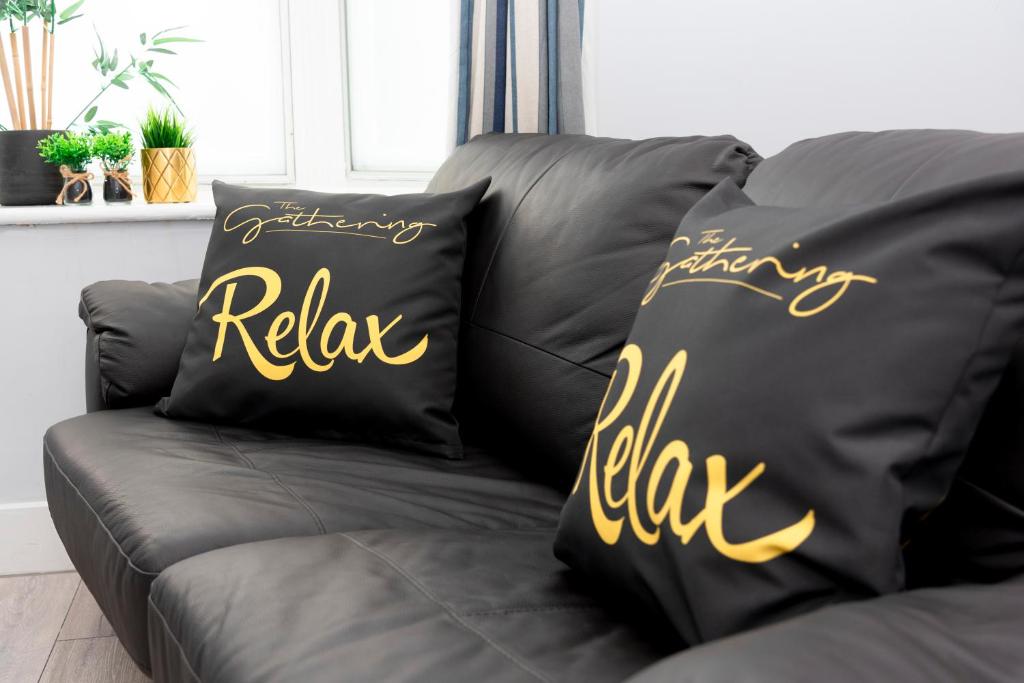 雷克瑟姆Wrexham Central Stay - Apartment Six的两个黑色枕头,上面写着单词,在沙发上放松