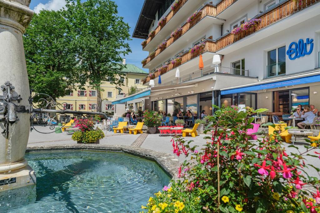 巴特霍夫加施泰因Hotel Blü Gastein的一座建筑前的庭院,庭院里设有喷泉和鲜花