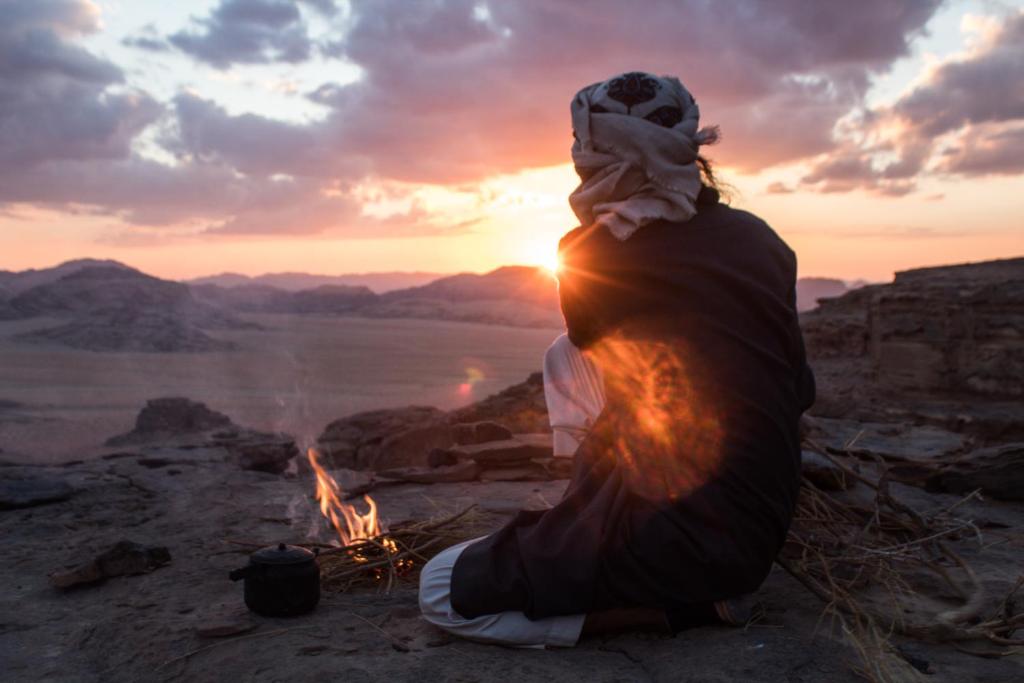 亚喀巴Bedouins life camp的坐在 ⁇ 火旁的女人,欣赏日落