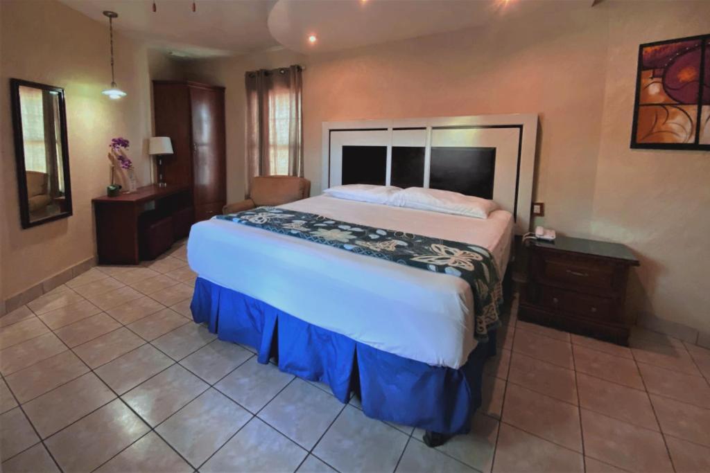 马塔莫罗斯Hotel Hacienda del Viejo的一间大卧室,配有一张大床和一把椅子