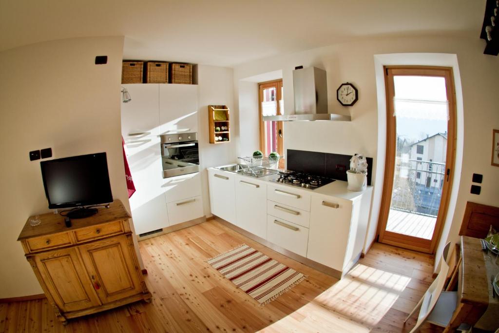 卡斯泰洛泰西诺Tesino Appartamenti 2的铺有木地板,设有带白色橱柜和电视的厨房。