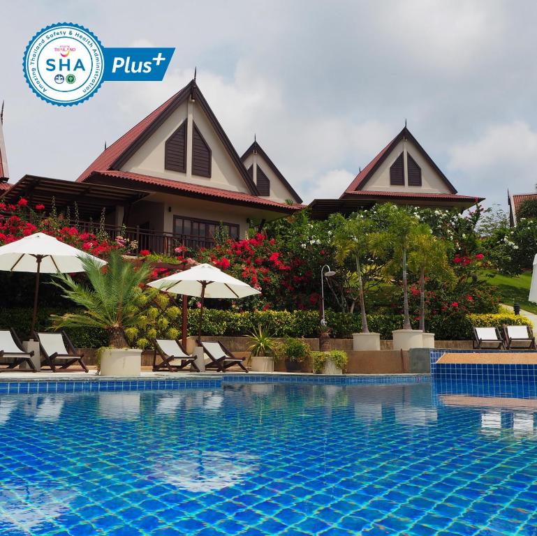高兰Baan KanTiang See Villas - SHA Extra Plus的一个带椅子和遮阳伞的游泳池的度假酒店