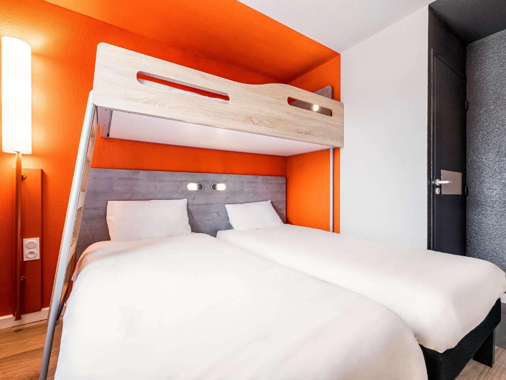 佩皮尼昂佩皮尼昂南宜必思快捷酒店的橙色墙壁的客房内的两张床