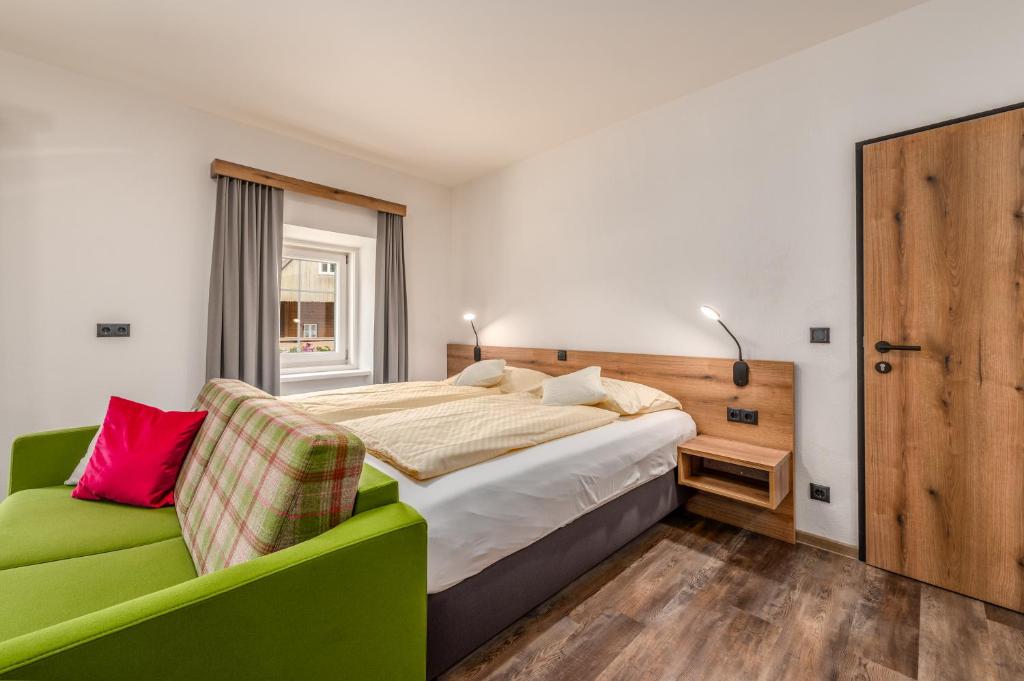 普鲁格恩Landgasthof Bierfriedl的一间卧室配有一张床和一张绿色沙发