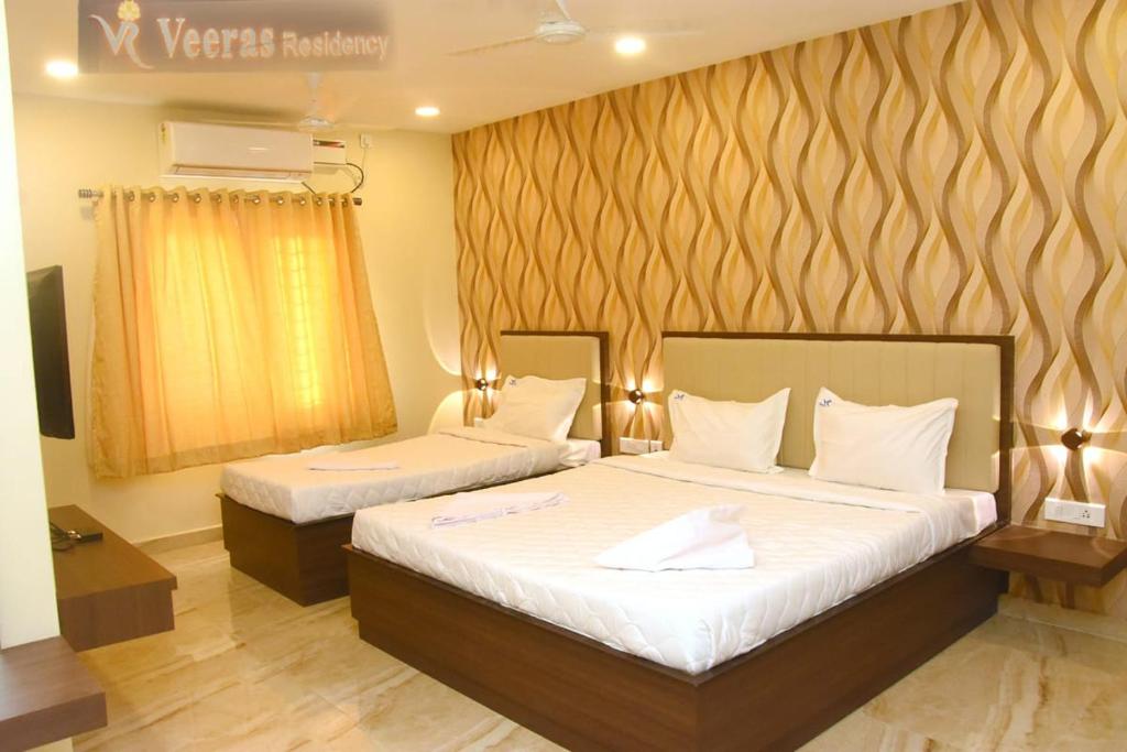 蓬蒂切里Veeras Residency的一间卧室配有两张带白色床单的床