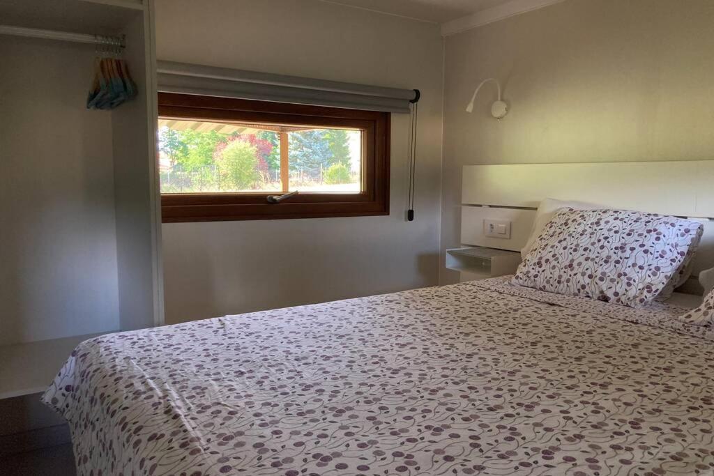乌娜Cabaña El Verdinal的卧室配有一张带白色棉被的床和窗户。