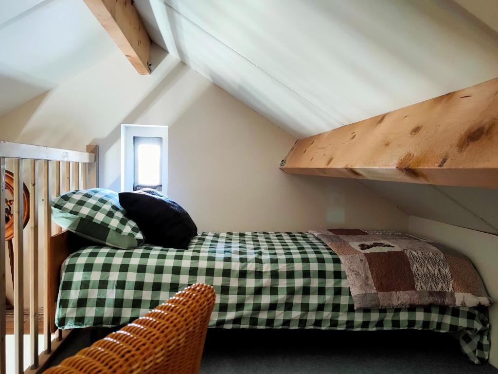 德摩尔b&b de Wensput的一间位于阁楼的卧室,配有绿色和白色的床