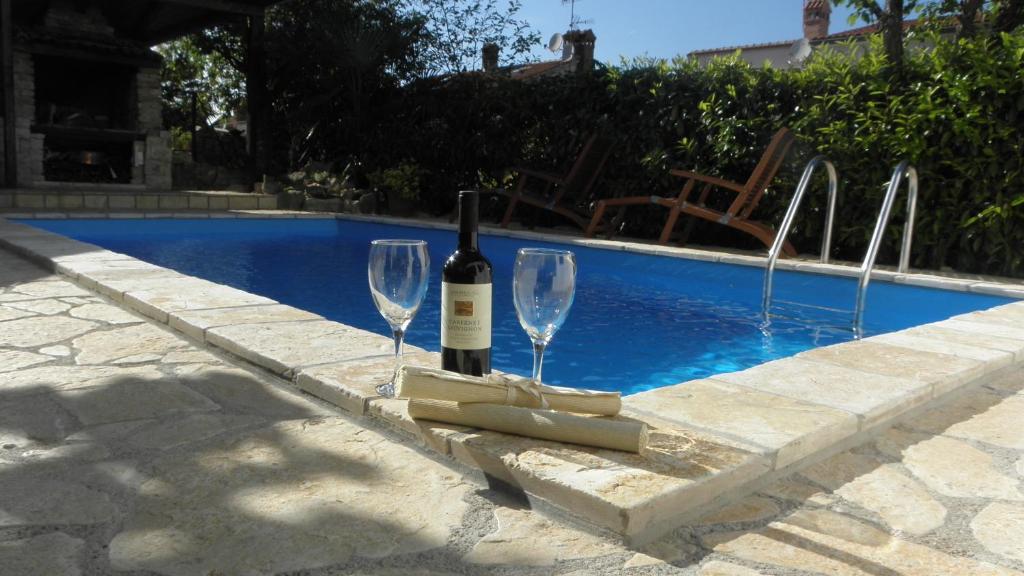 波雷奇Apartment Klesinger的游泳池旁的一瓶葡萄酒和两杯酒