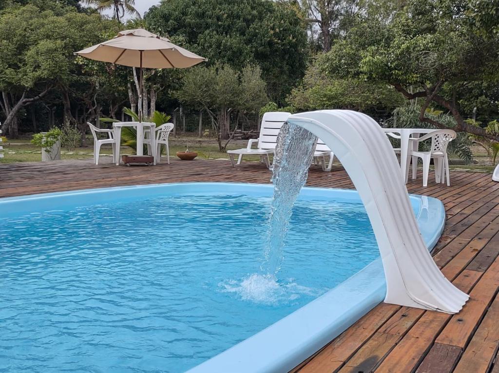 伊塔乌纳斯Pousada Nossa Casa的游泳池的滑水道,带雨伞