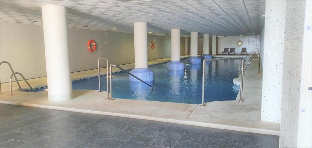 比卡尔La envia golf的一座建筑物内一座游泳池,游泳池里拥有柱子和蓝色的水