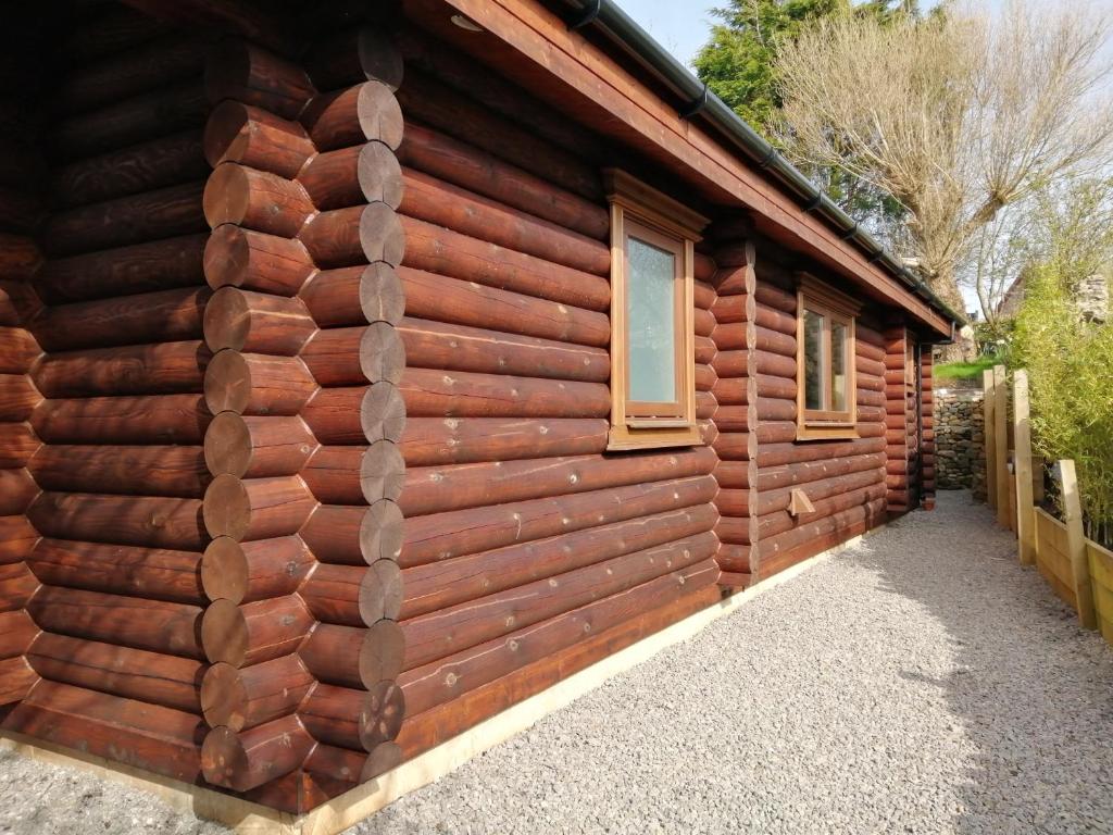雷文格拉斯Ravenglass Log Cabin的小木屋的一侧,设有2扇窗户