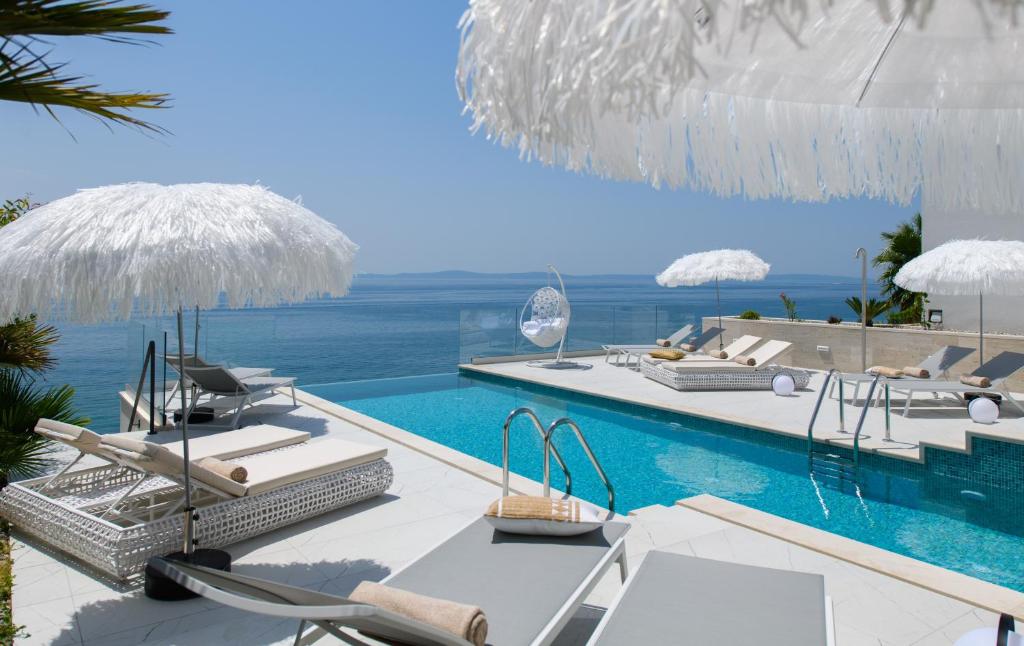 斯普利特Gallery Luxury Suites & Rooms-Only Adults的一个带椅子和遮阳伞的游泳池以及大海
