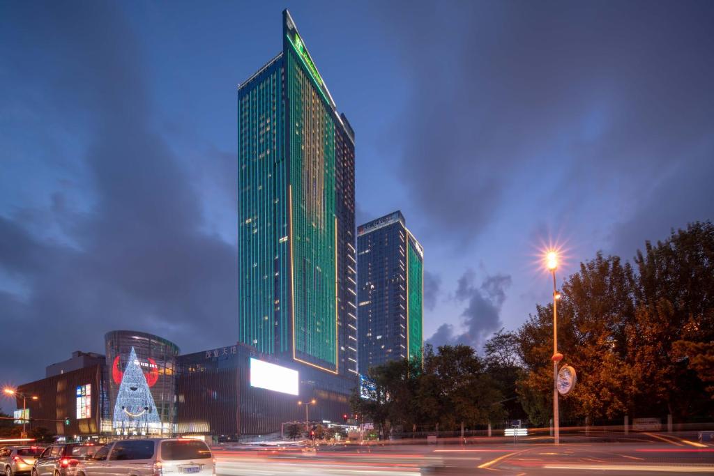 秦皇岛秦皇岛茂业中心假日酒店的一座高大的绿色建筑,前面有圣诞树
