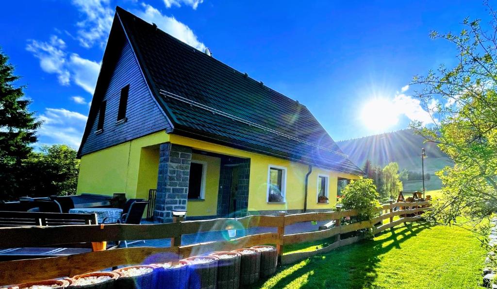 奥泊维森塔尔Ferienwohnung-direkt-am-skihang的一间黄色的小房子,有黑色的屋顶