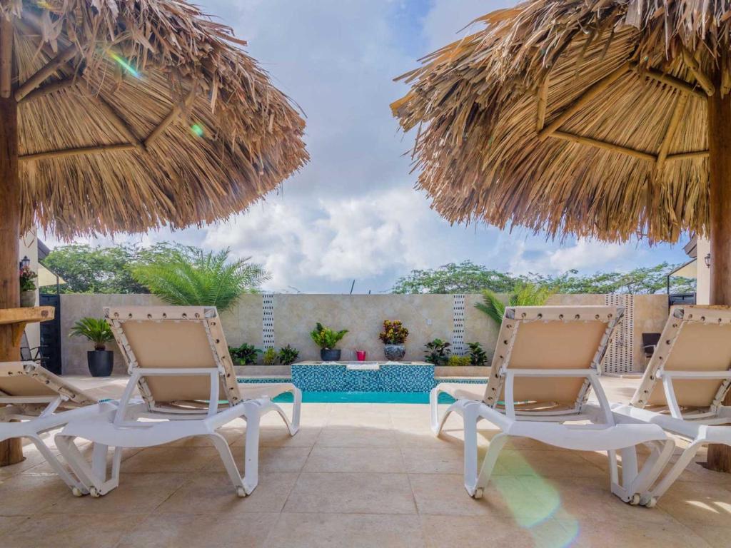 棕榈滩金色别墅式酒店的一个带两把椅子和两把遮阳伞的庭院
