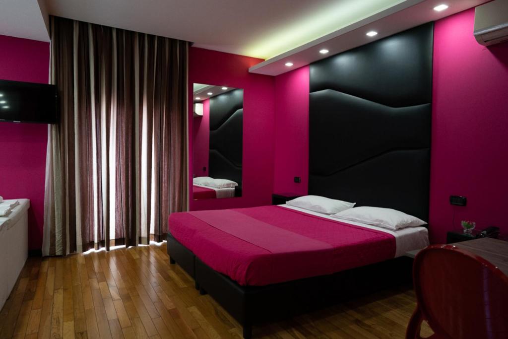 卡塞塔Sweet Central Hotel的粉红色的卧室,配有一张带黑色床头板的床
