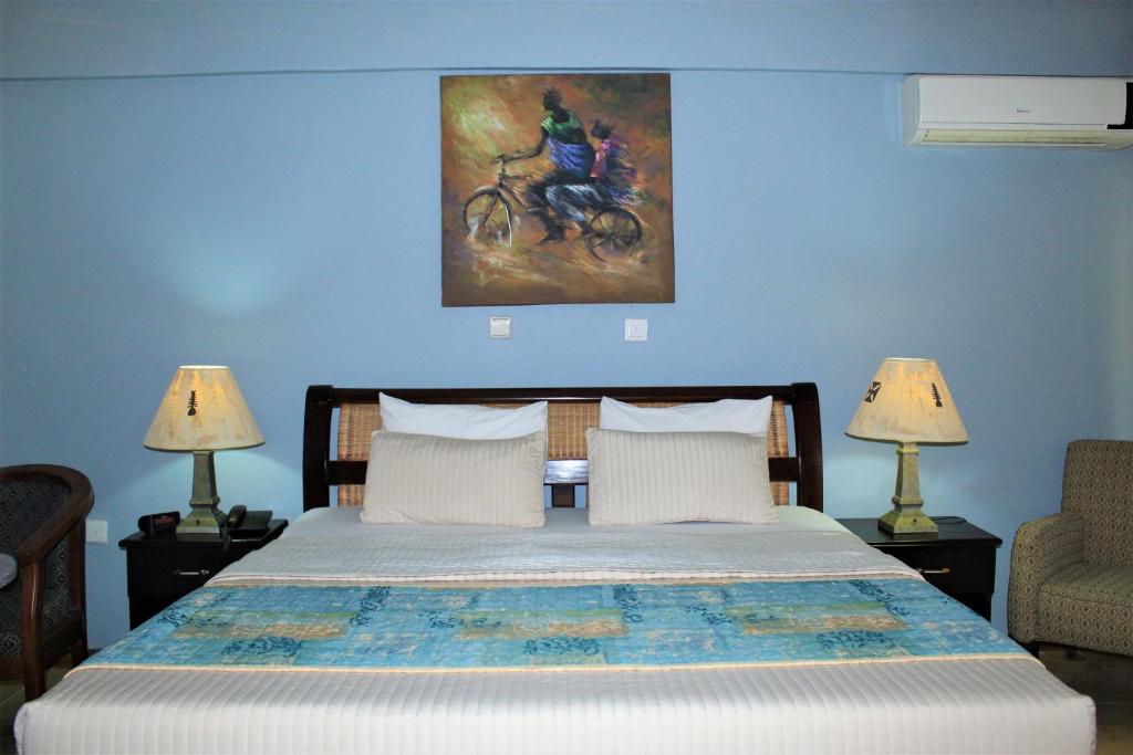 Bortianor博约海滩度假酒店的卧室配有一张床,墙上挂有绘画作品