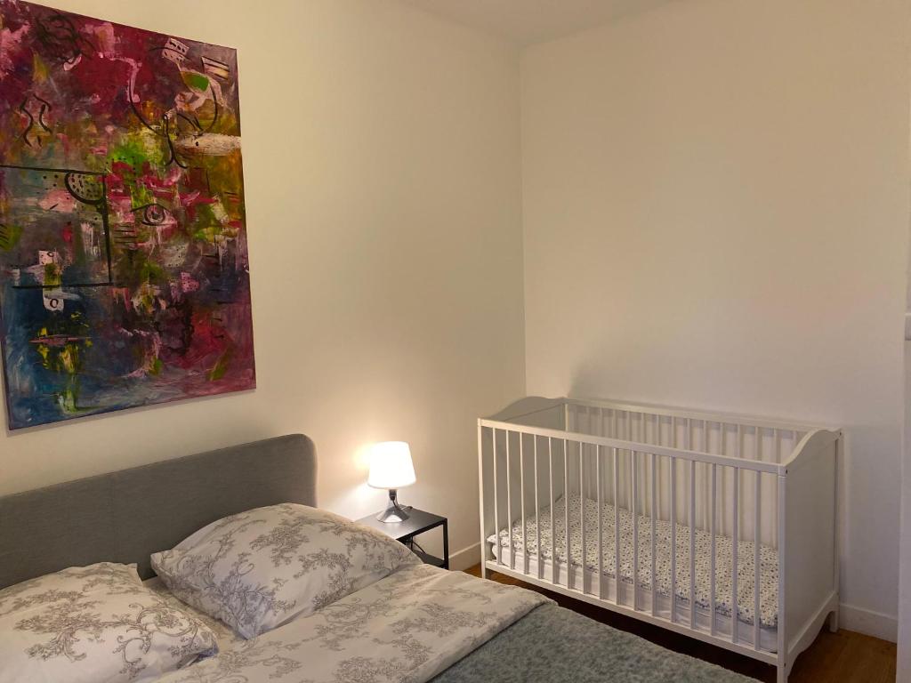 La BonnevilleMaison chaleureuse avec un grand jardin的卧室配有婴儿床,墙上挂有绘画作品