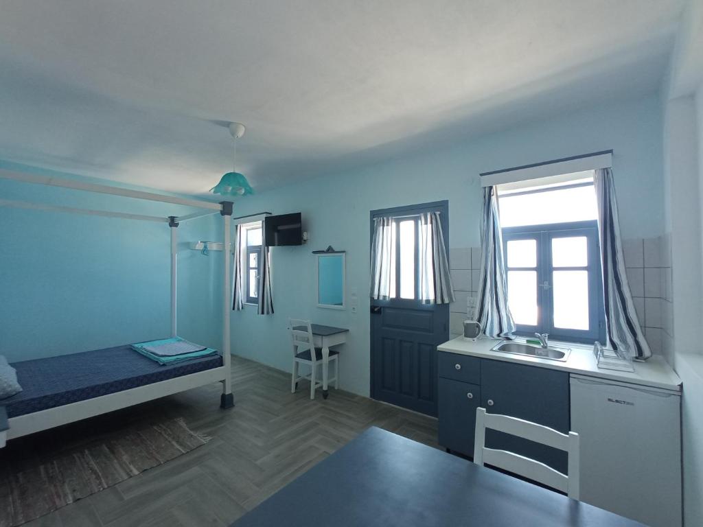 OlymposAnemos Guest House Karpathos的客房设有床、书桌和窗户。