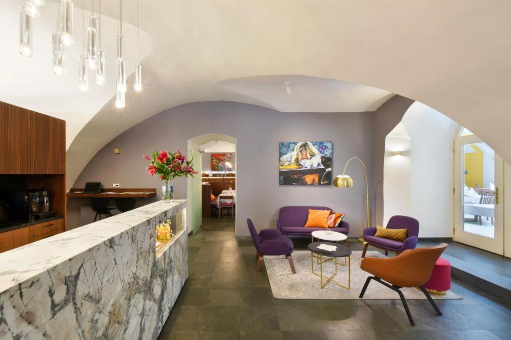 格拉茨Boutique Hotel Dom - Rooms & Suites的客厅配有紫色椅子和石墙