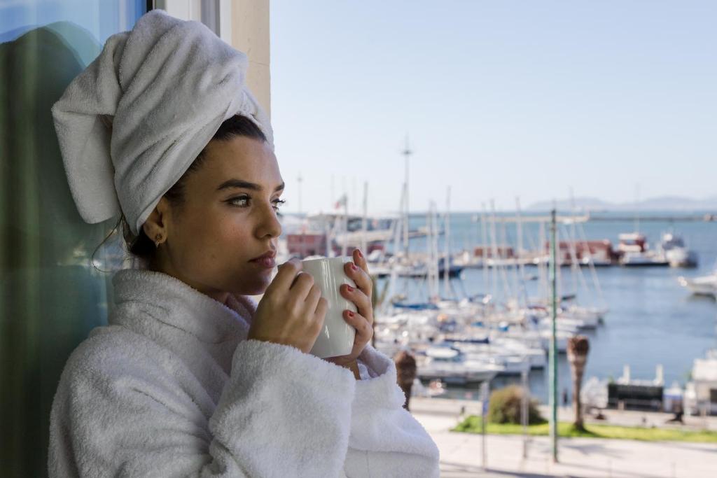 卡利亚里Hotel Aristeo的妇女用毛巾,拿着咖啡