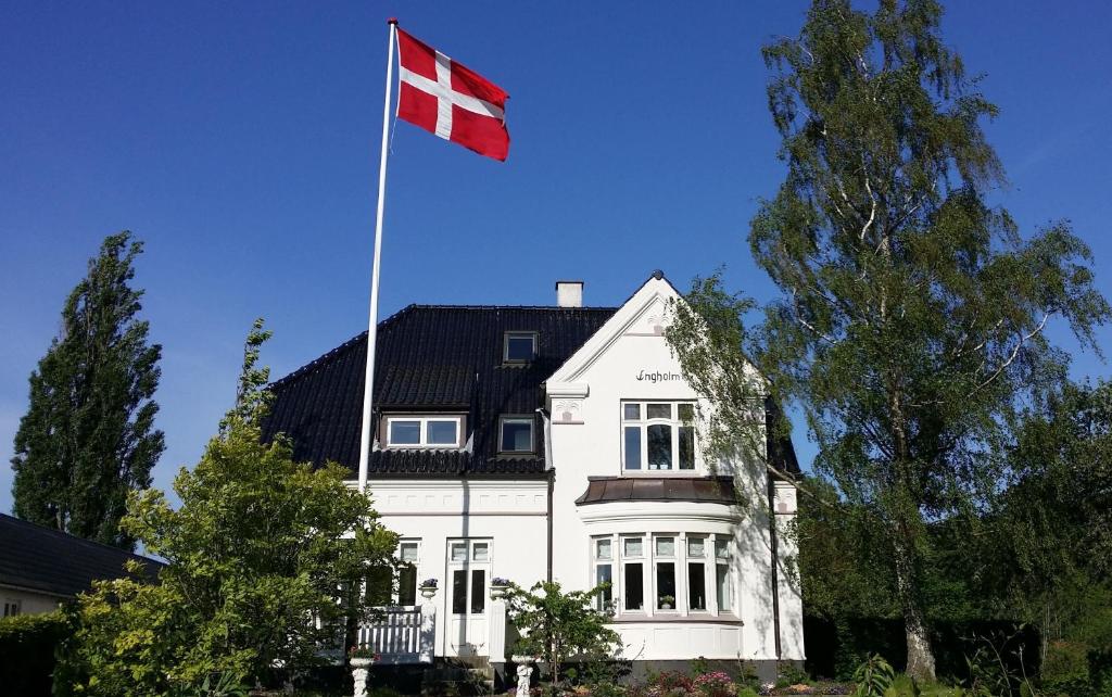 欧登塞恩格霍姆住宿加早餐旅馆的白色的房子,上面有旗帜