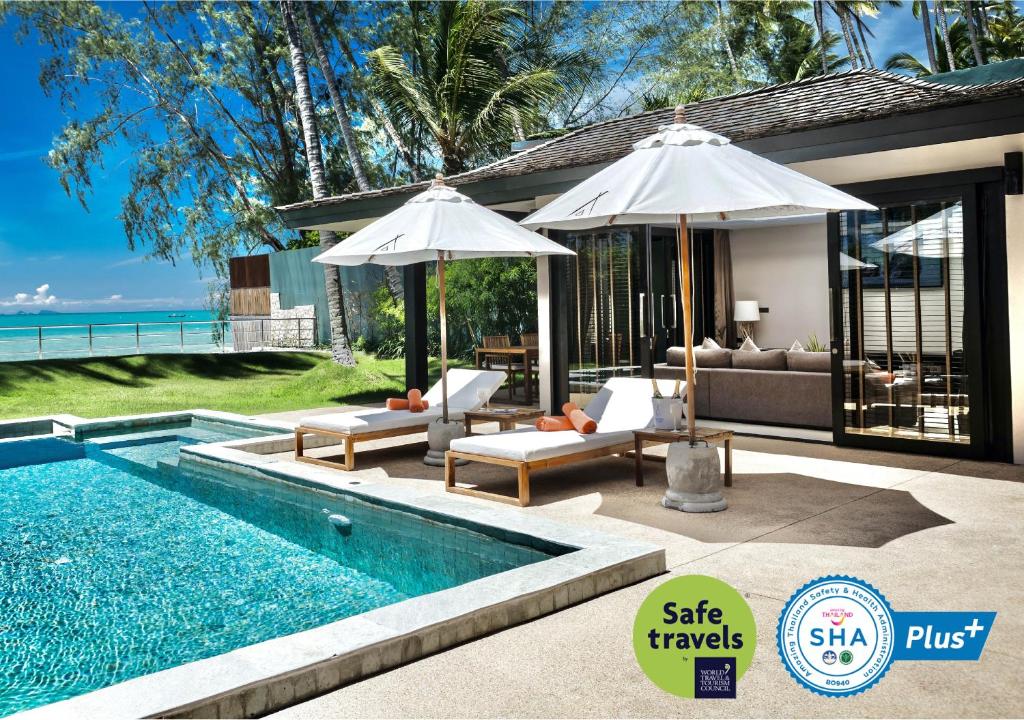 利巴诺伊Nikki Beach Resort & Spa Koh Samui的一个带遮阳伞的游泳池和一个房子