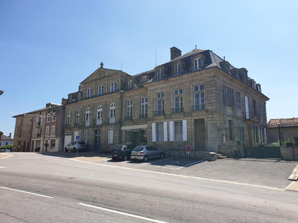 ChâteauponsacLe Chateau的一座大型砖砌建筑,前面有汽车停放