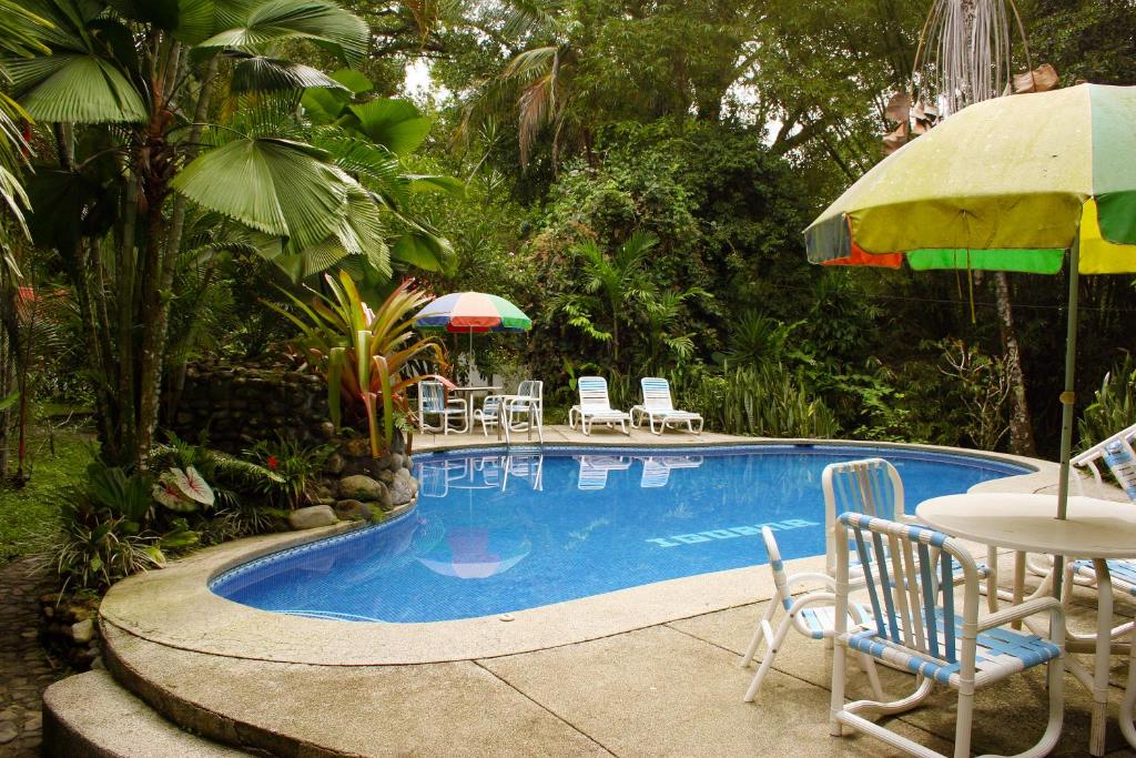 卡维塔Cabinas Iguana Cahuita的一个带桌椅和遮阳伞的游泳池