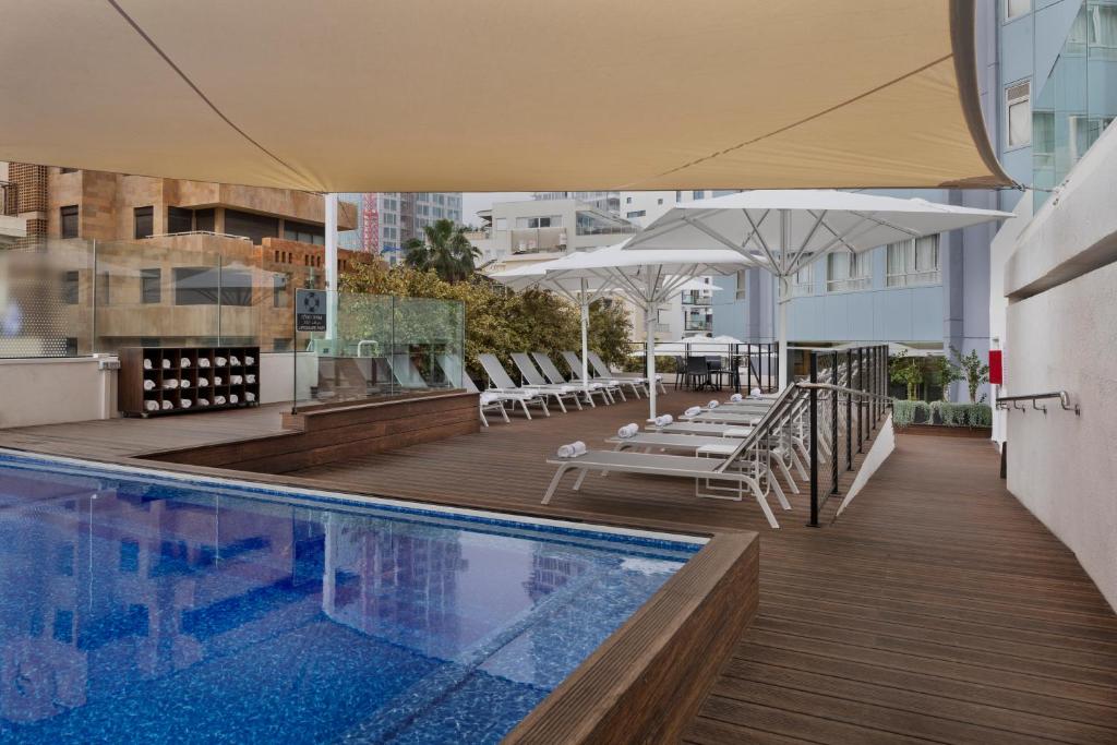 特拉维夫大都会酒店的大楼内带椅子和遮阳伞的室外游泳池