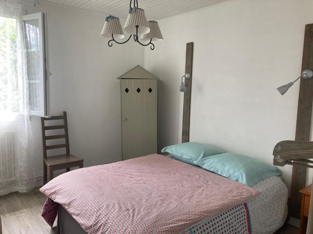 波讷地区圣朱利安Appartement 2/3 personnes à 10 minutes de Contis plage (Saint Julien en Born)的一间卧室配有一张床、一把椅子和一个吊灯。