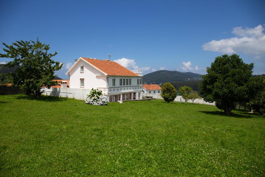 VillarrubeBeachfront Surf & Holiday House, up to 12 persons的绿色田野上红色屋顶的白色房子