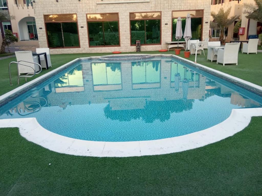 阿吉曼Corniche Palace Hotel的大楼前的蓝色海水游泳池