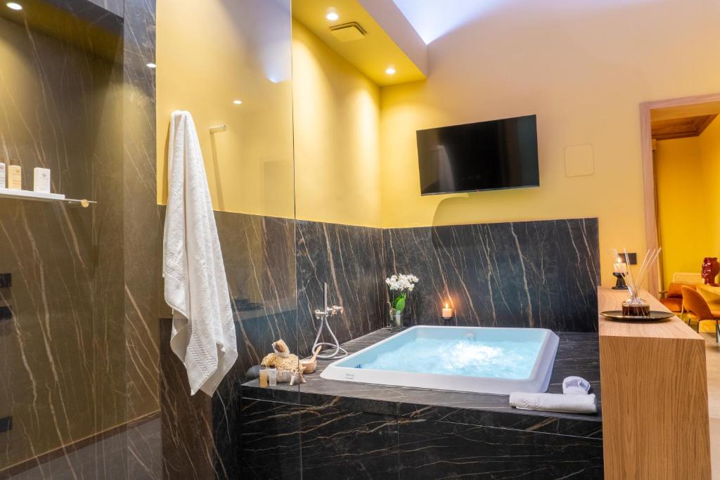 卡塔尼亚ETNEA Suite 270的带浴缸的浴室和墙上的电视
