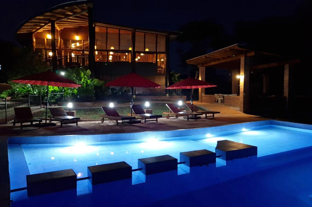 埃尔索韦维奥Puro Moconá Lodge的夜间游泳池,配有椅子和遮阳伞