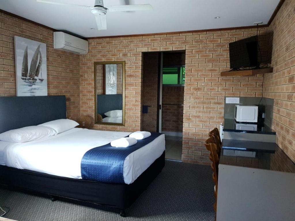 Pacific Paradise Pacific Paradise Airport Motel的一间卧室设有床铺、电视和砖墙